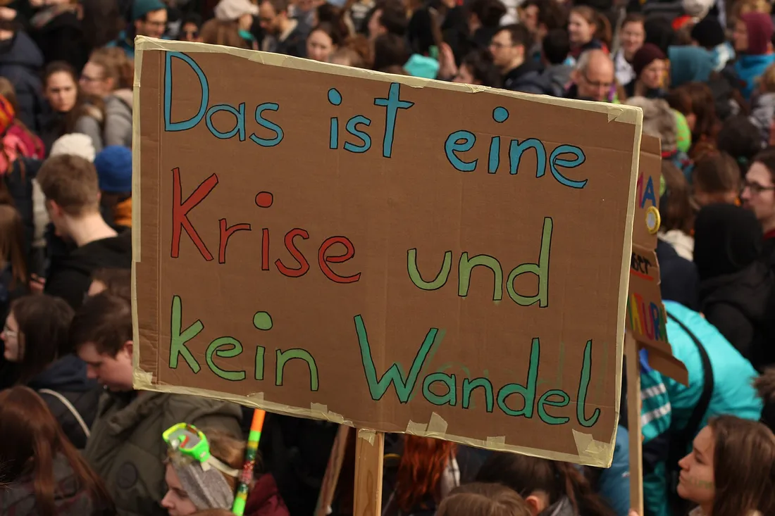 Handgemaltes Kartonschild in der Menge: Das ist eine Krise und kein Wandel